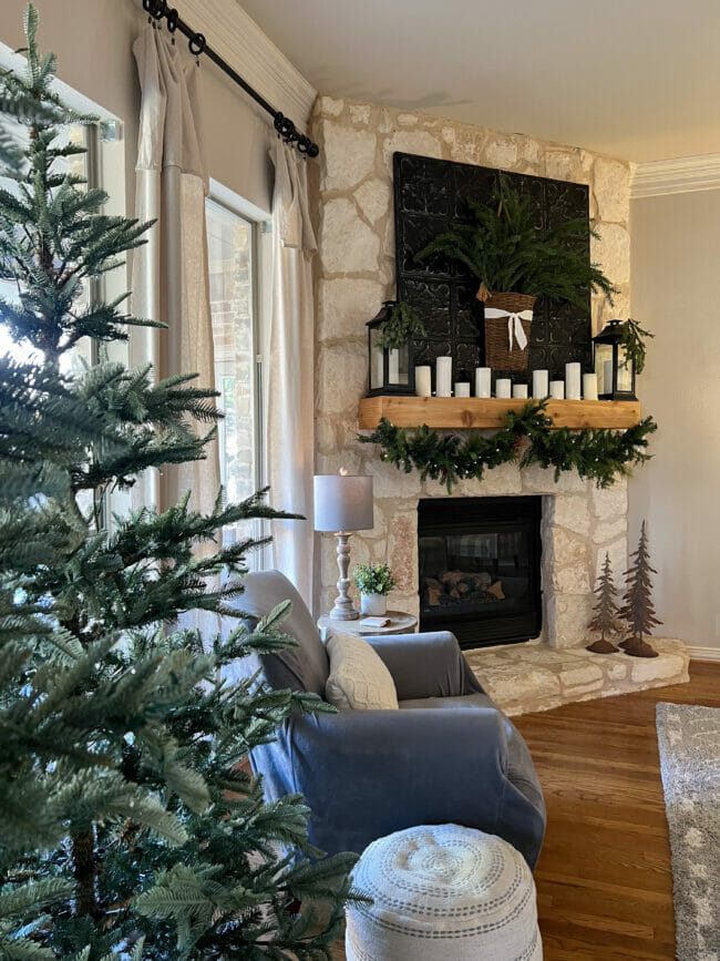 stone mantel in corner with Christmas trees and garland