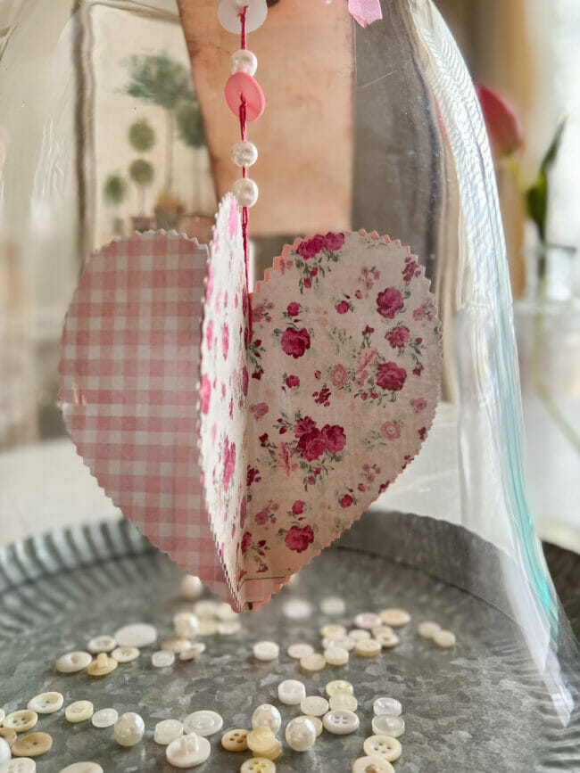 paper heart with roses and buttons inside galvanized tray and hanging from a cloche