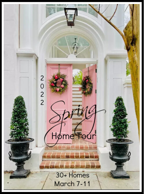 pink open front door with wreaths and topiaries