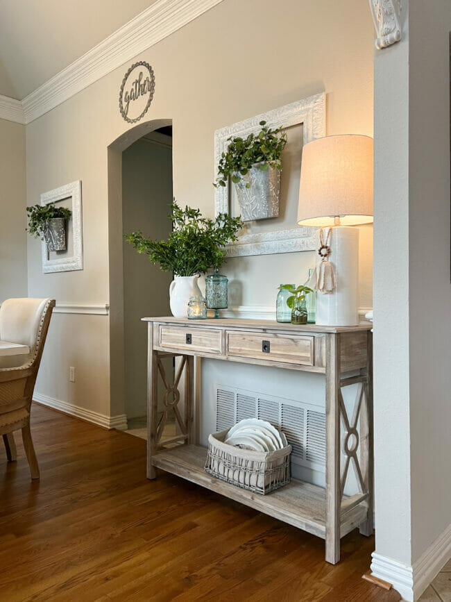 spring console table with plants, lamp and basket with dishes on bottom