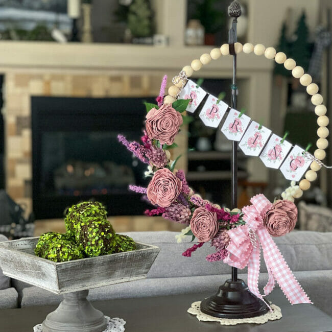 bead wreath hanging on stand with greenery balls