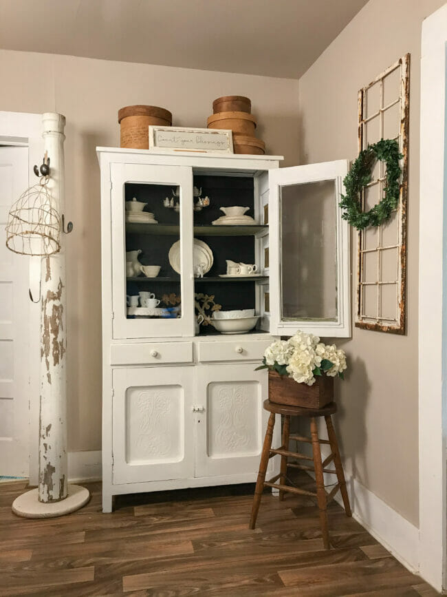 dining hutch with stool and flowers on top and column in corner
