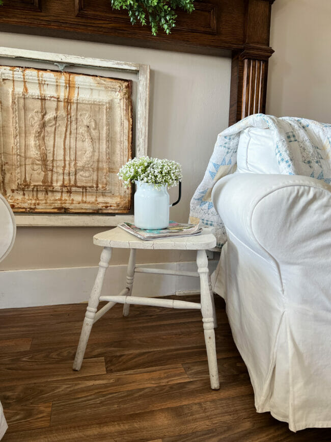 white slip covered chair with old chair used as table with flowers on it