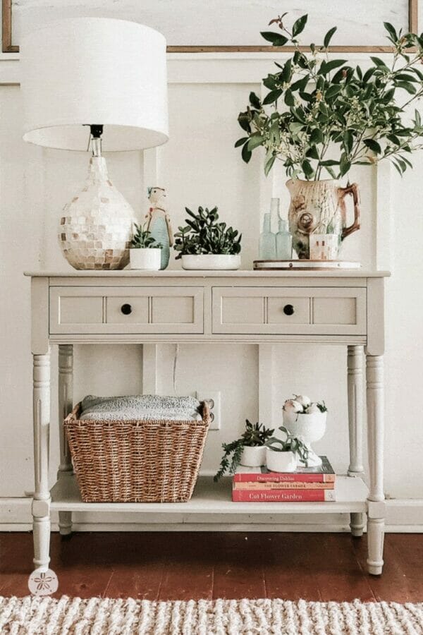 console table with lamp, plants, basket and books