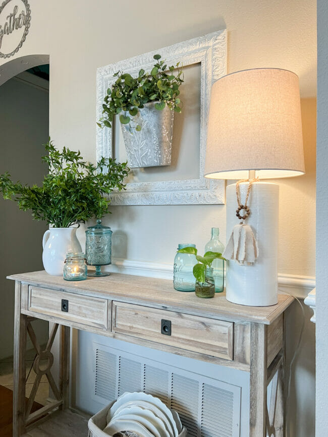 console table with lamp, plants and blue bottles
