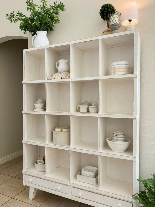 white cubby shelf with white pottery
