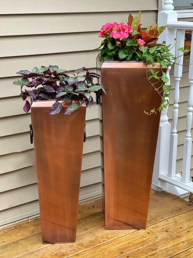 two tall rusty planters with flowers