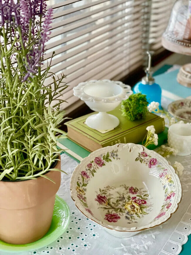 Table with antique bowl, potted plant and white candy dish