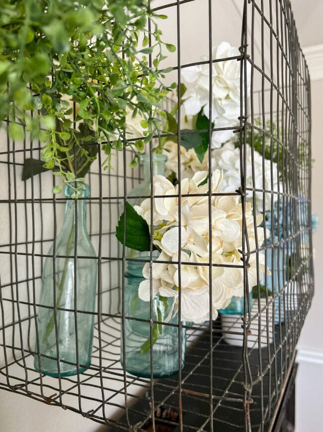 metal cage with blue bottles and hydrangeas
