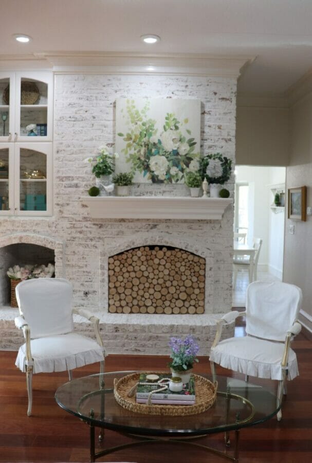 living room with white chairs, white brick and spring mantel