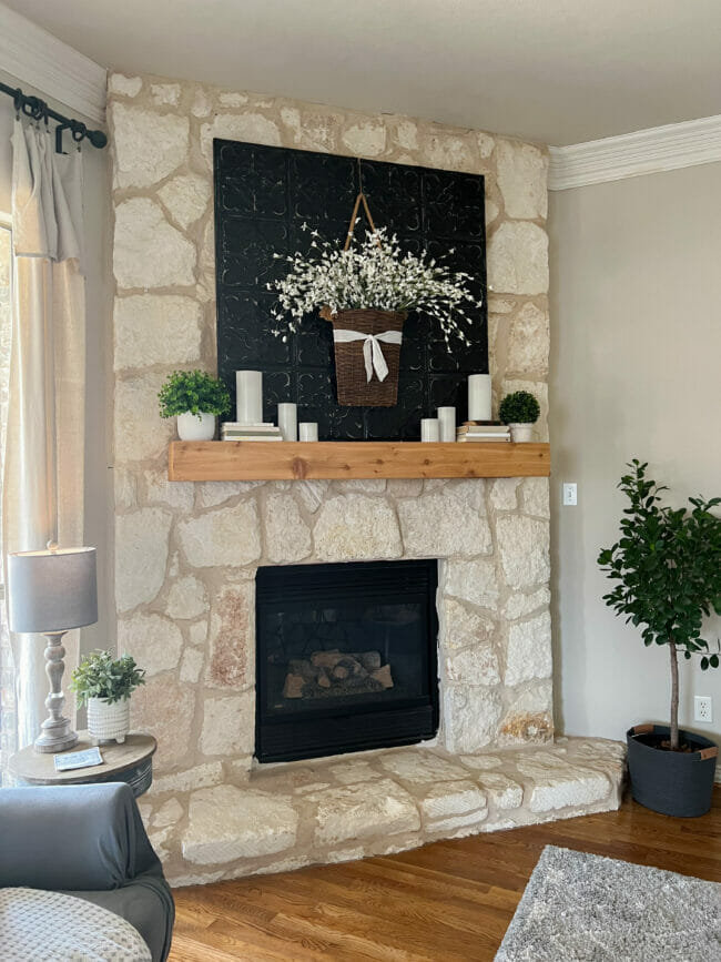 stone fireplace with white candles, flowers hanging in basket and candles