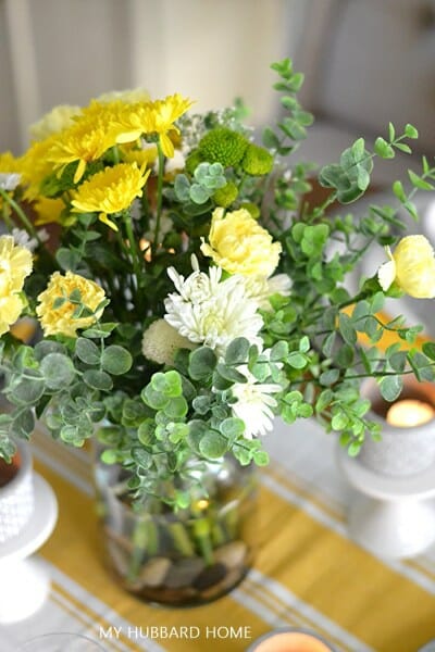 boquet of yellow and white flowers on a tablecloth