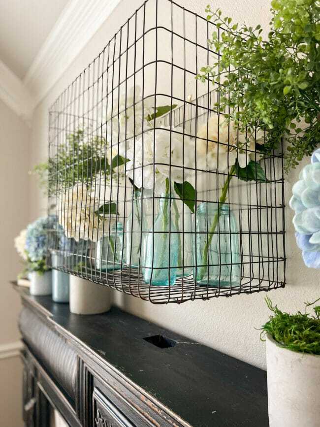 old metal chicken wire box with bottles and flowers