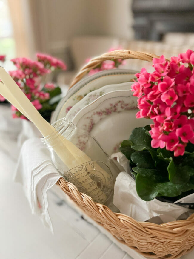 basket filled with candles, plates, potted flowers and vintage napkins