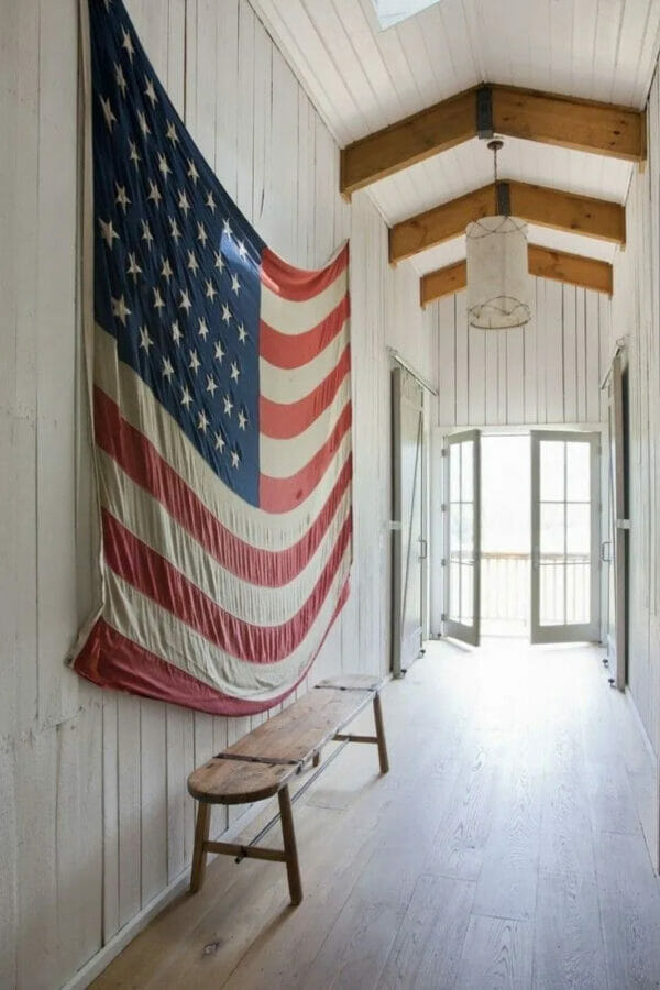 large flag hanging on white wall with bench underneath