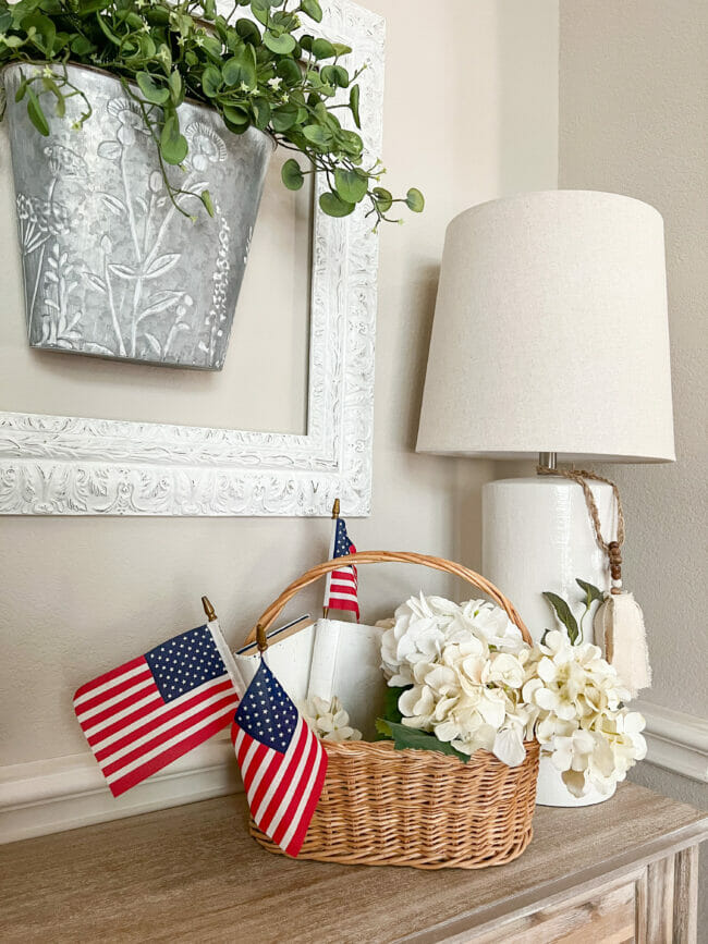 basket with white flowers and mini flags with a lamp and frame on wall