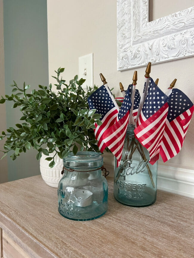 mini flags inside vintage blue jar with plant and small jar with candle