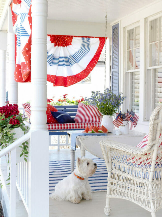 BHG porch with bunting, white wicker chairs and white Westie dog