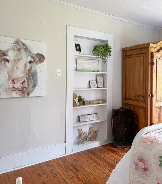 farmhouse decorated book shelves with cow print on wall