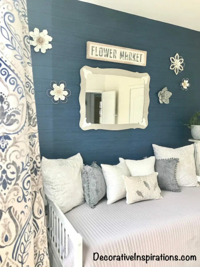dark blue wall with flowers, mirror and a daybed with pillows