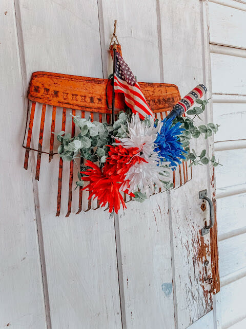 vintage rake with red, white and blue decor hanging on it