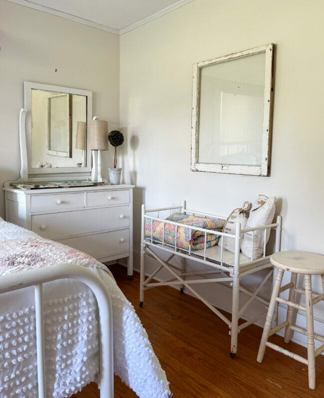 vintage baby bed with quilt, chest of drawers with mirror and a stool