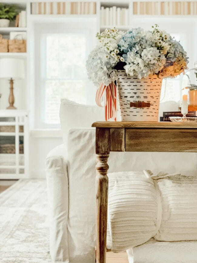 wood table with white sofa and bucket of hydrangeas on top