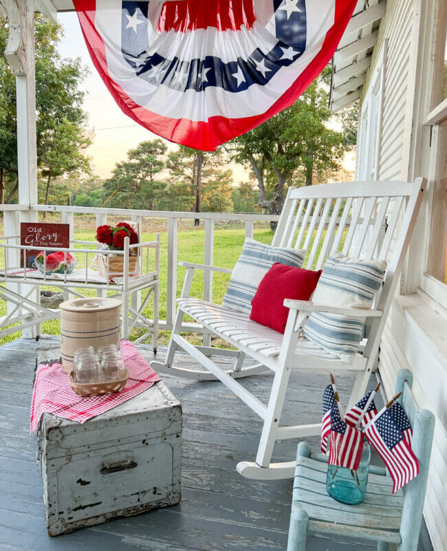 white rocking bench with pillows, a banner and other patriotic decor