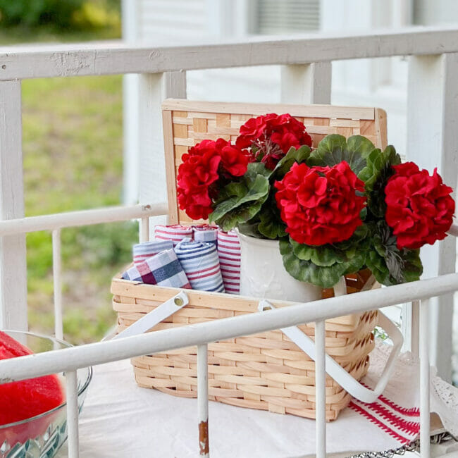 red geraniums in picnic basket with cloth napkins