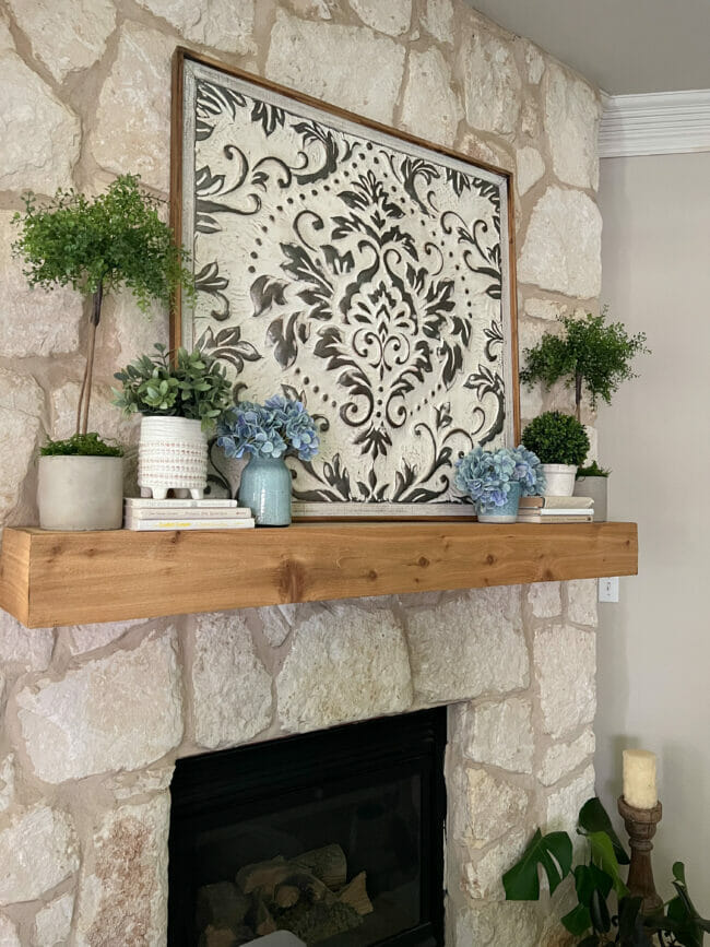mantel with large metal damask frame, topiaries and blue vases with hydrangeas