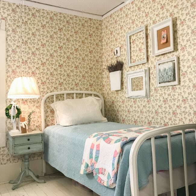 country bedroom with wallpaper, twin bed, side table and hanging lamp