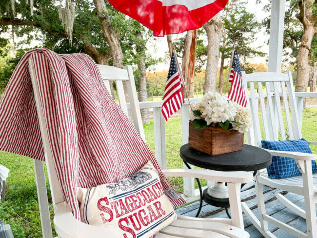 two white rocking chairs with patriotic pillows and flags
