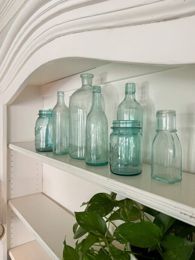 vintage blue bottles on top shelf of white hutch
