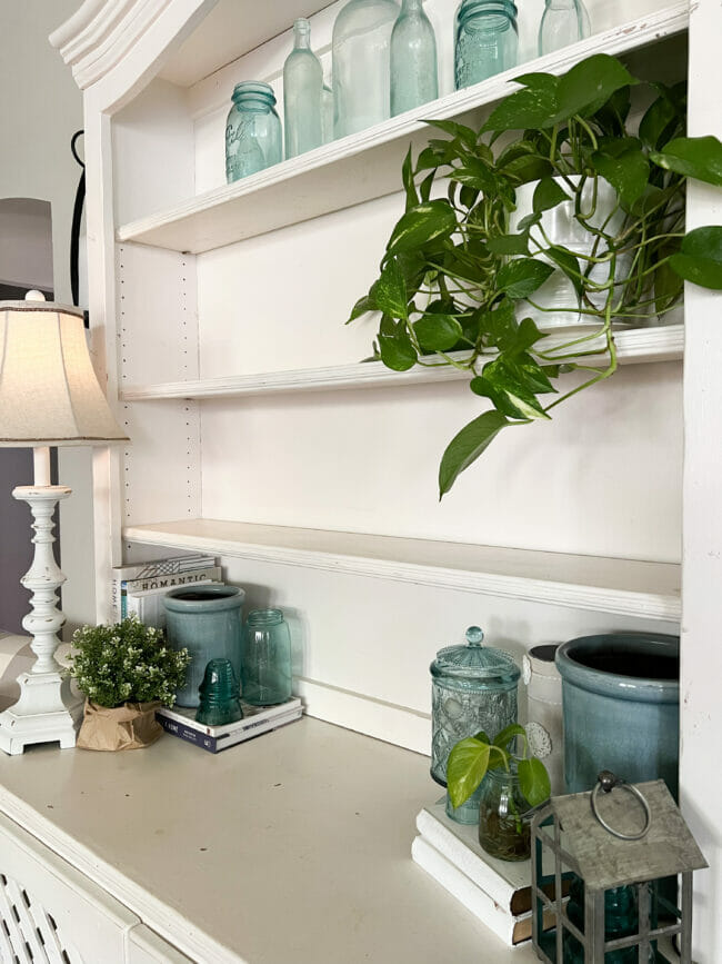 white hutch shelves with plant, lamp, and blue accessories