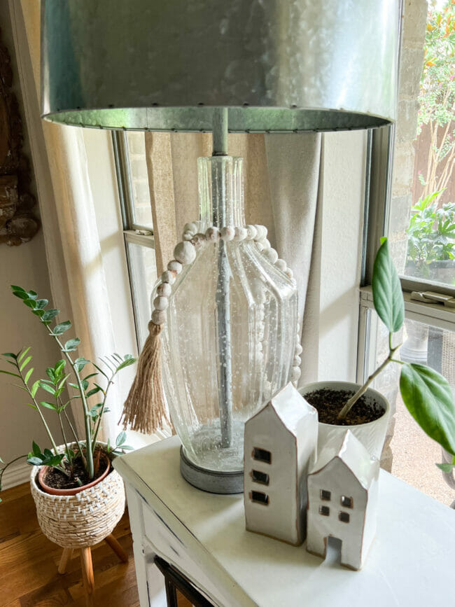 clear lamp on table with small white houses and plants
