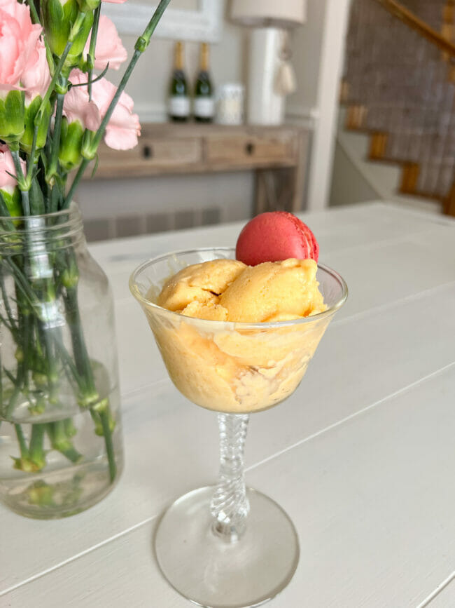 peach sherbet in glass with macaron and flowers