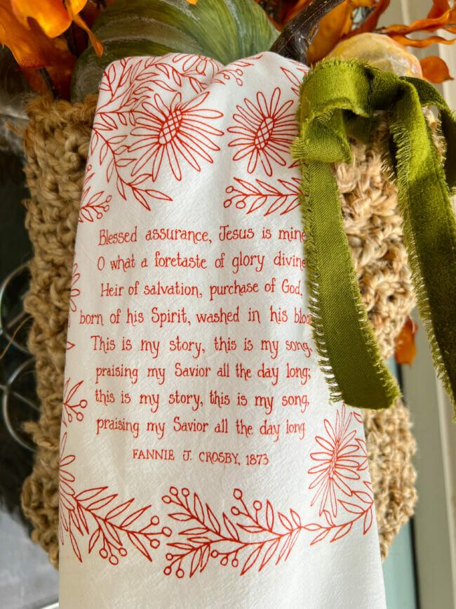 Blessed Assurance tea towel and green ribbon hanging on basket