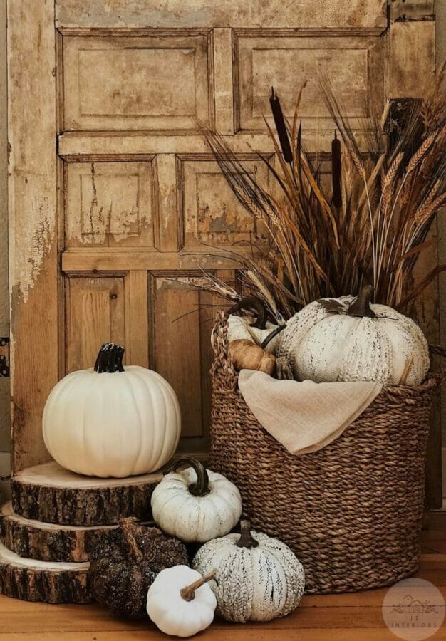 wood door with basket of white pumpkins and stems sitting in front of it.
