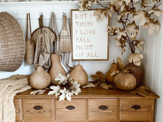 gourds and leaves on a wood chest with a fall sign on wall
