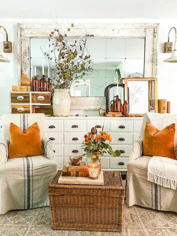 vintage white chest with chairs and orange pillows and fall stems