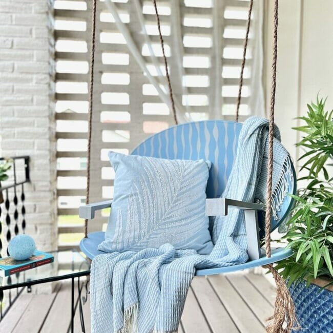 blue swing and blanket with pillow hanging on porch