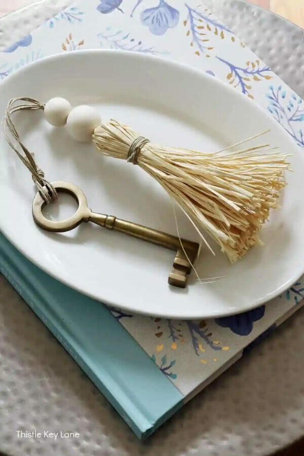 Rafia tassel on white platter with old key attached