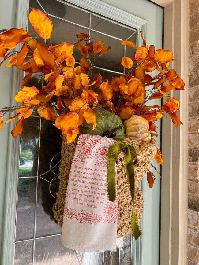 fall basket with orange stems, pumpkins and a tea towel