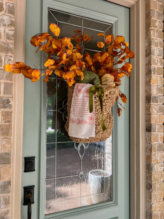 pale green front door with fall basket hanging on it.