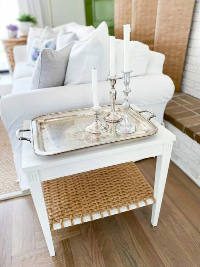 white sofa with white side table with silver tray and candles on it.