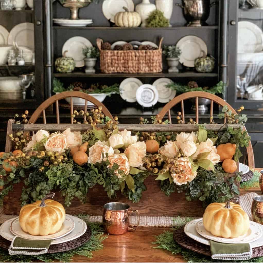 gold and green floral centerpiece with fall pumpkins at each place setting