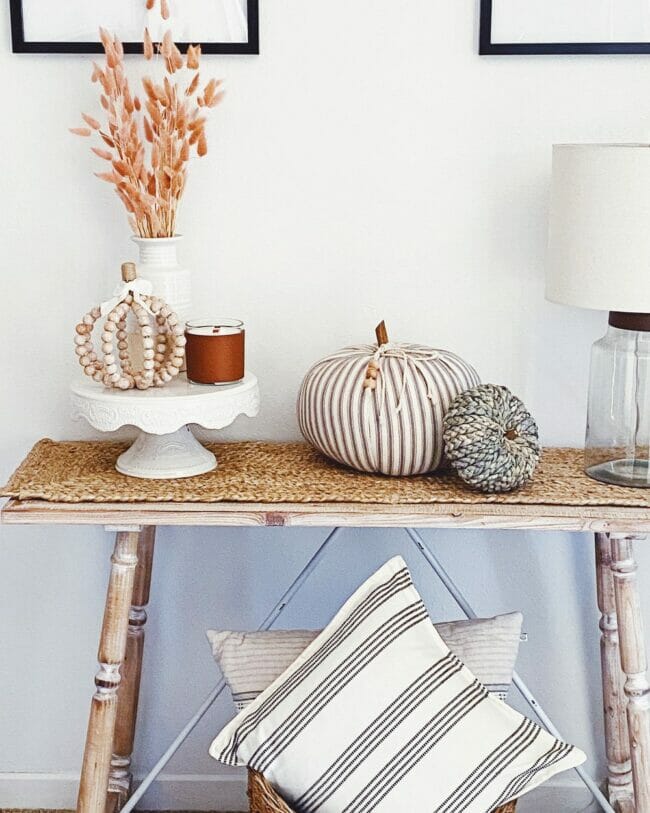 console table with pumpkins and fall stems on cake plate