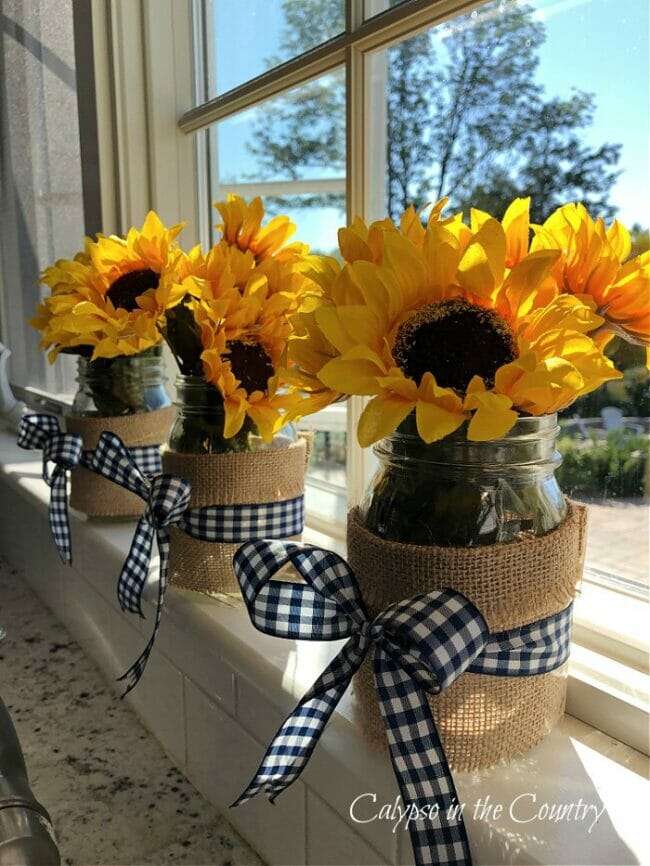 3 sunflower vases with black and white ribbon sitting in window
