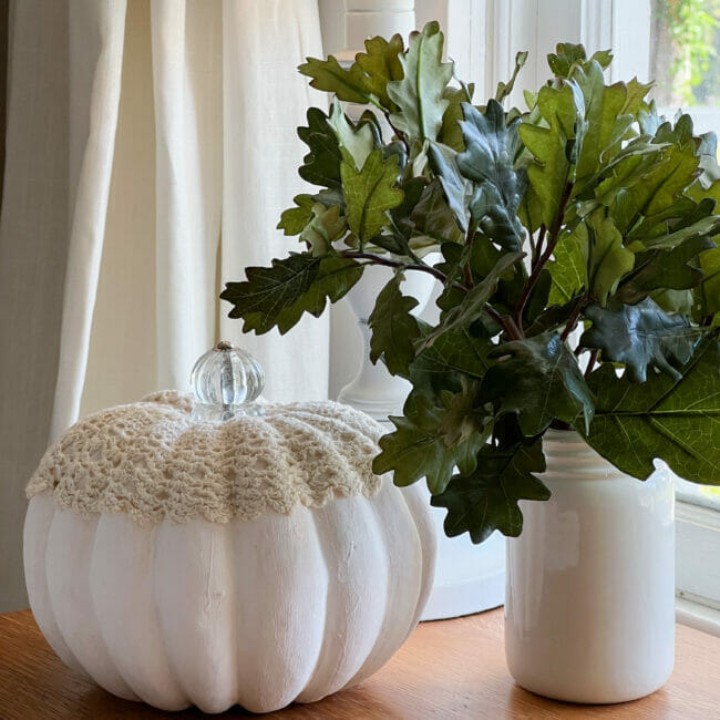 white pumpkin with crocheted doily and oak leaves in white jar