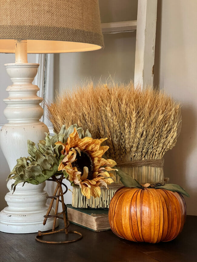 sunflowers, wheat and orange pumpkin on table